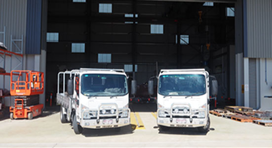 Two White Trucks In front of Roller Shutter Doors